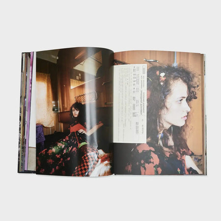 Open fashion book displaying editorial photos of a woman in patterned clothing indoors