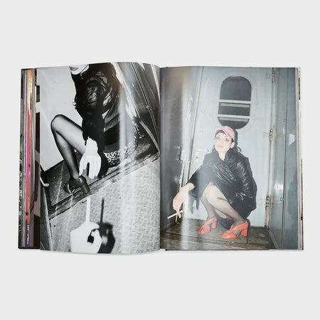 Fashion photo book open to images of a woman in a leather jacket, tights, and red heels