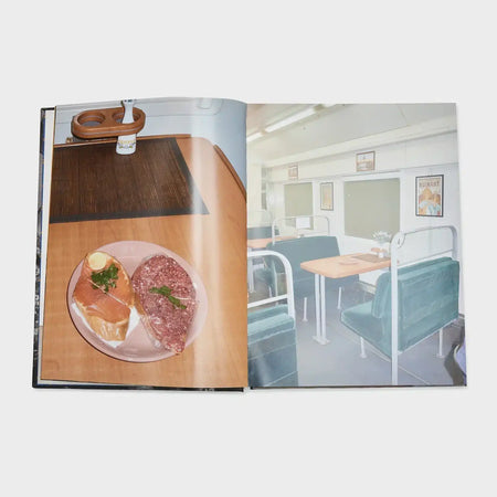 Open book displaying a train dining car interior and plate of sandwiches on a table