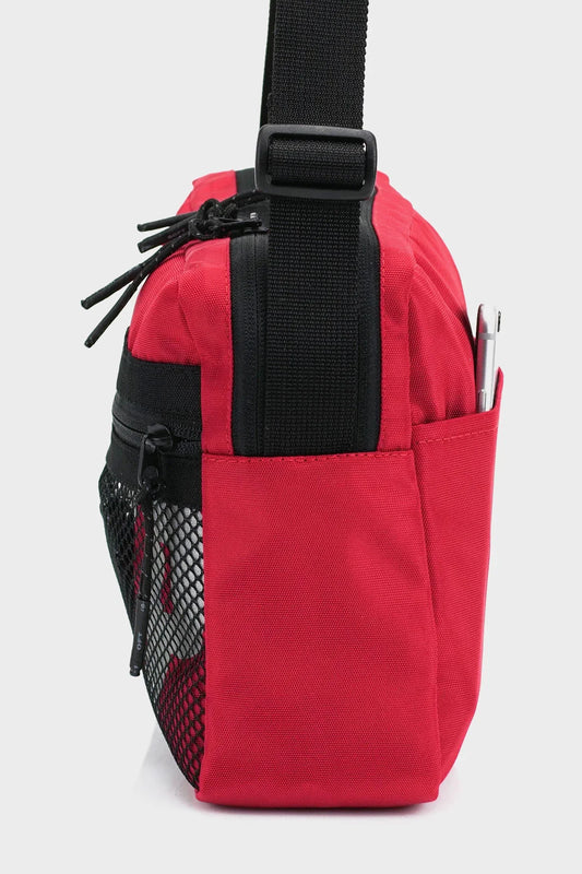 Side view of red crossbody bag with black strap, mesh pocket, and phone holder
