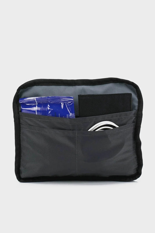 Black travel pouch with front pockets containing a blue packet, cord, and black item
